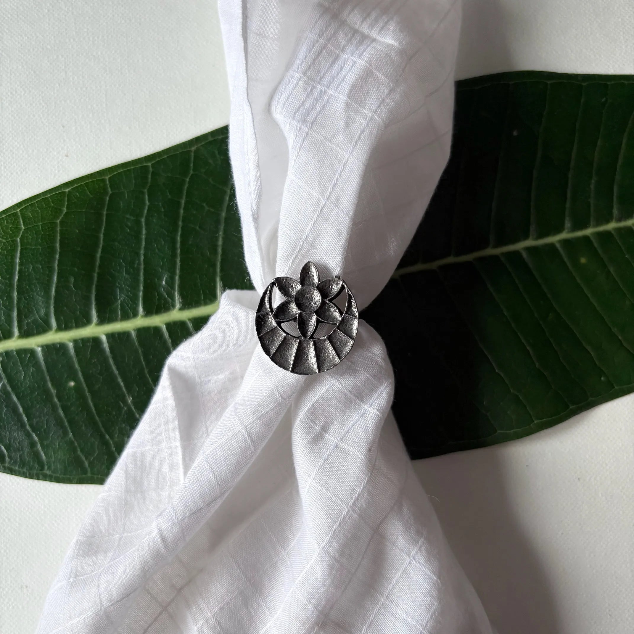 Chandrapushpa oxidised brass tribal ring with engraved floral motif, displayed on a green leaf – Complimento handcrafted jewelry.