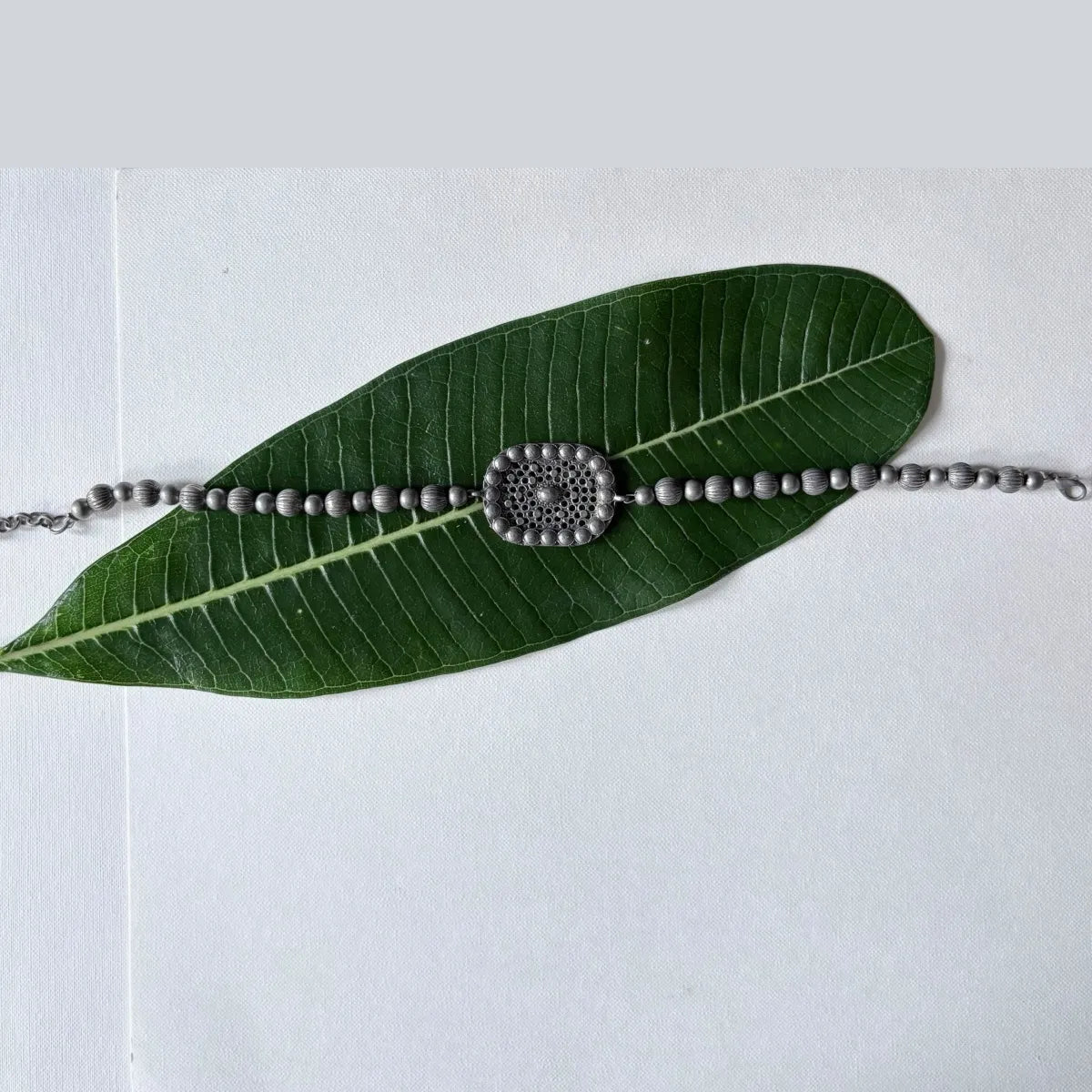 Flatlay of Jalakriti oxidised brass ball choker necklace with central tribal motif – Complimento
