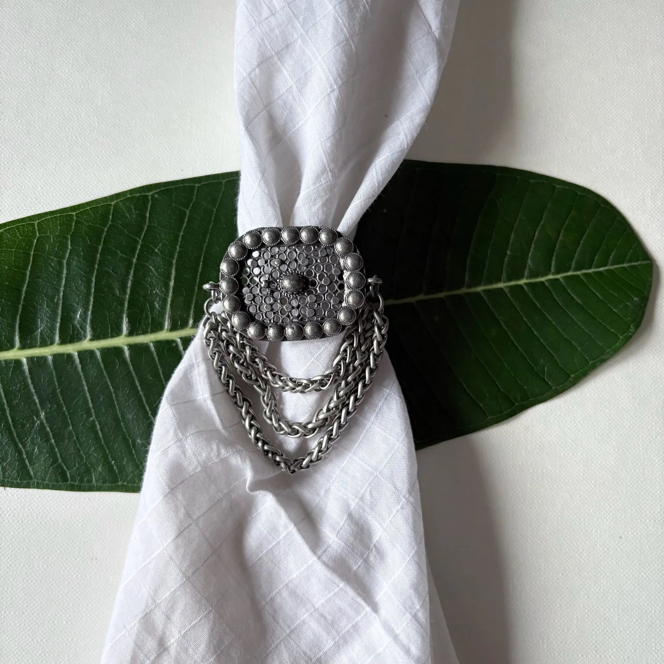 Flatlay of Jalakriti oxidised brass chain ring with tribal motif and bracelet-style chain by Complimento
