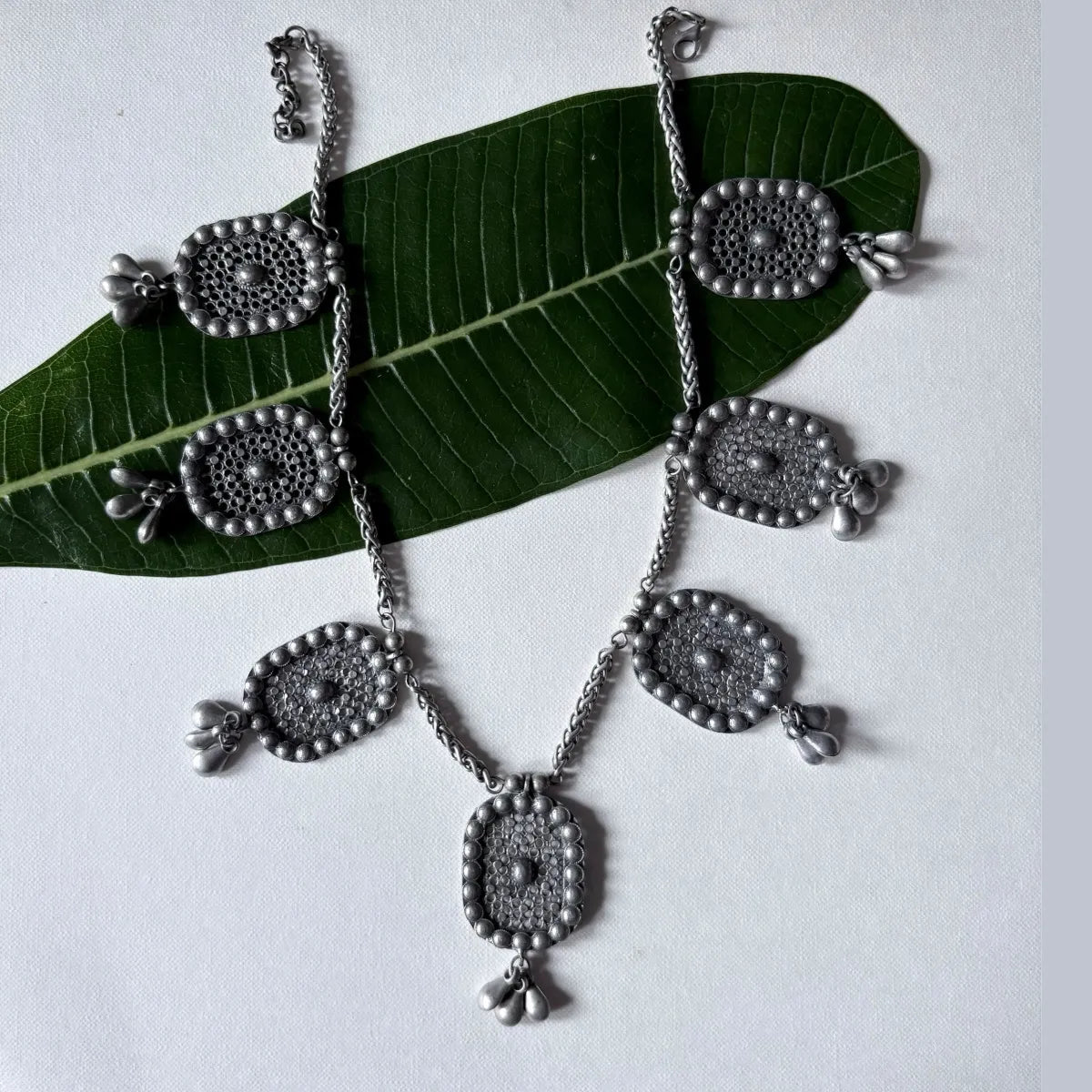 Full view of Jalakriti Hanging Charm Necklace with floral charms and bead chain on white backdrop
