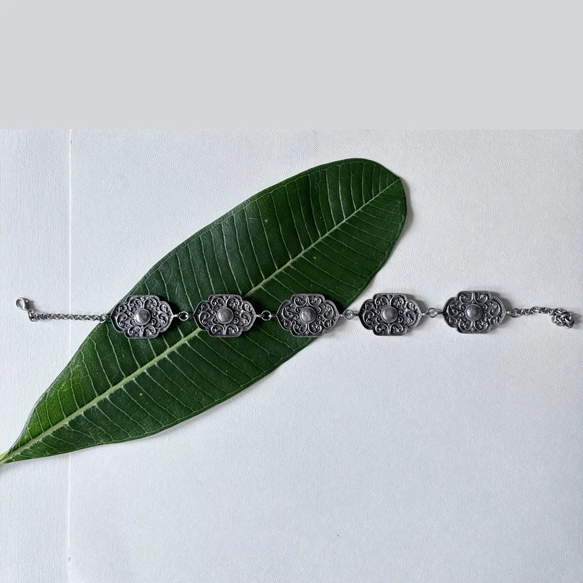 Flatlay of floral oxidised choker plates on leaf background – Complimento handmade jewelry
